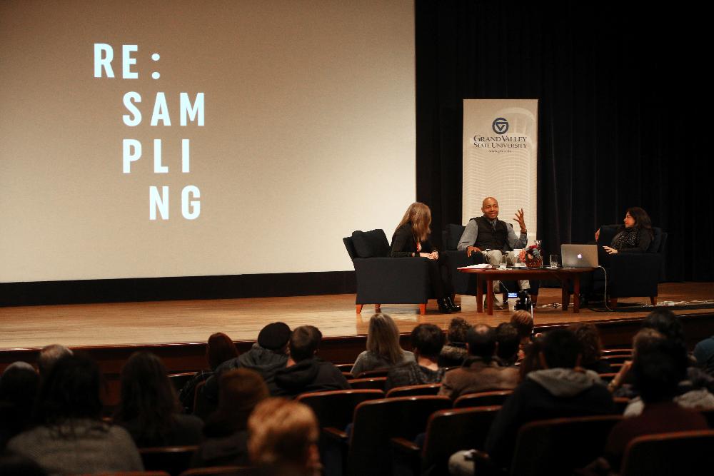 Three individuals sitting in front of projector screen saying SAMPLING